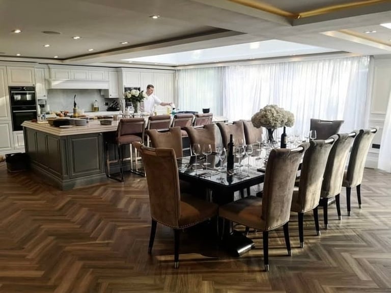 Luxury modern kitchen and dining area with island, dining table seating eight, and chef in background